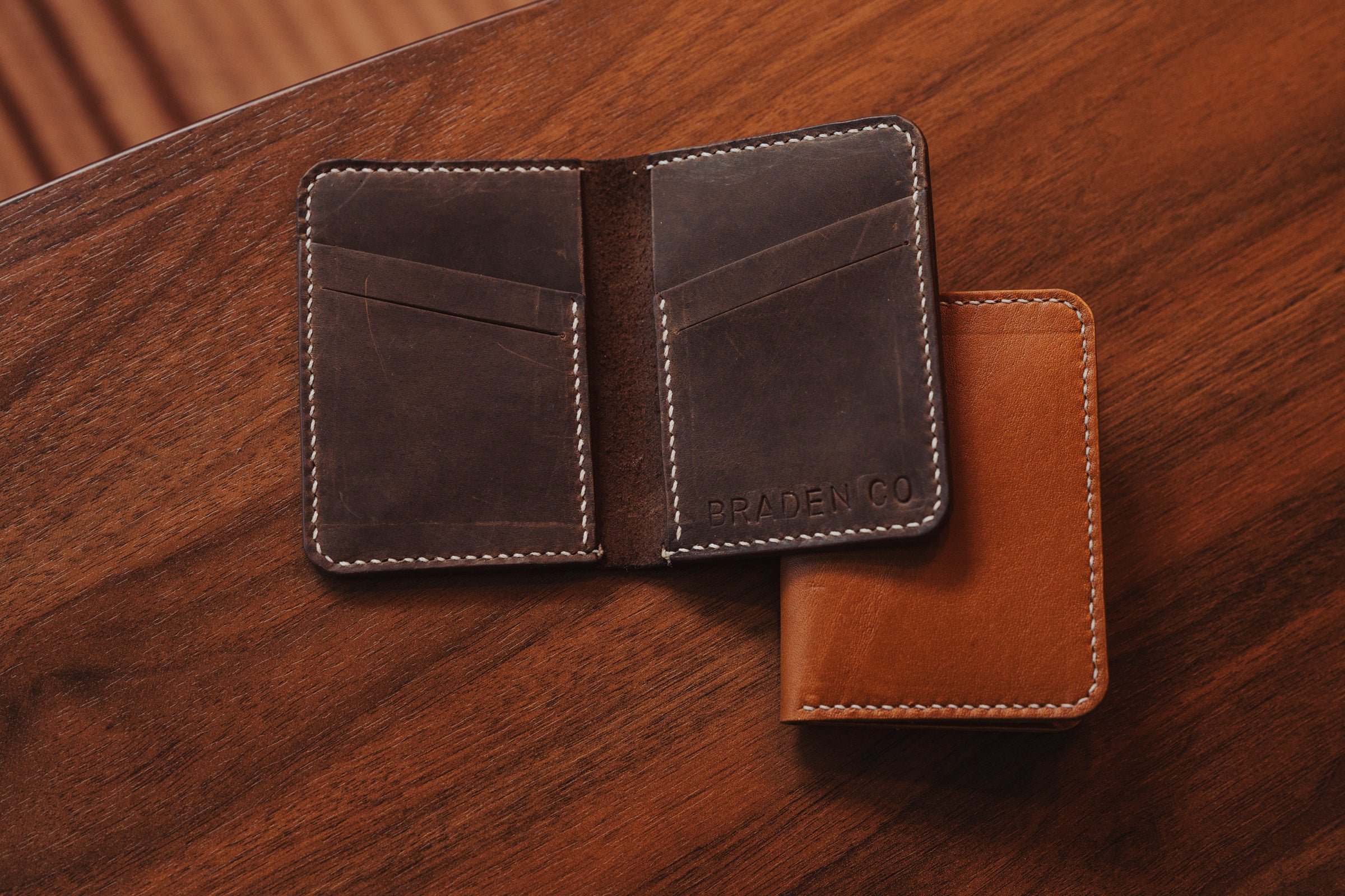 Brown leather wallet with visible brand name on a wooden surface