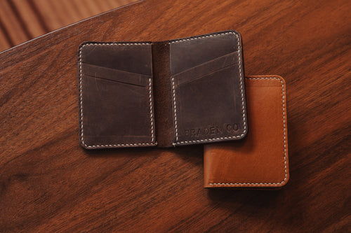 Brown leather wallet with visible brand name on a wooden surface