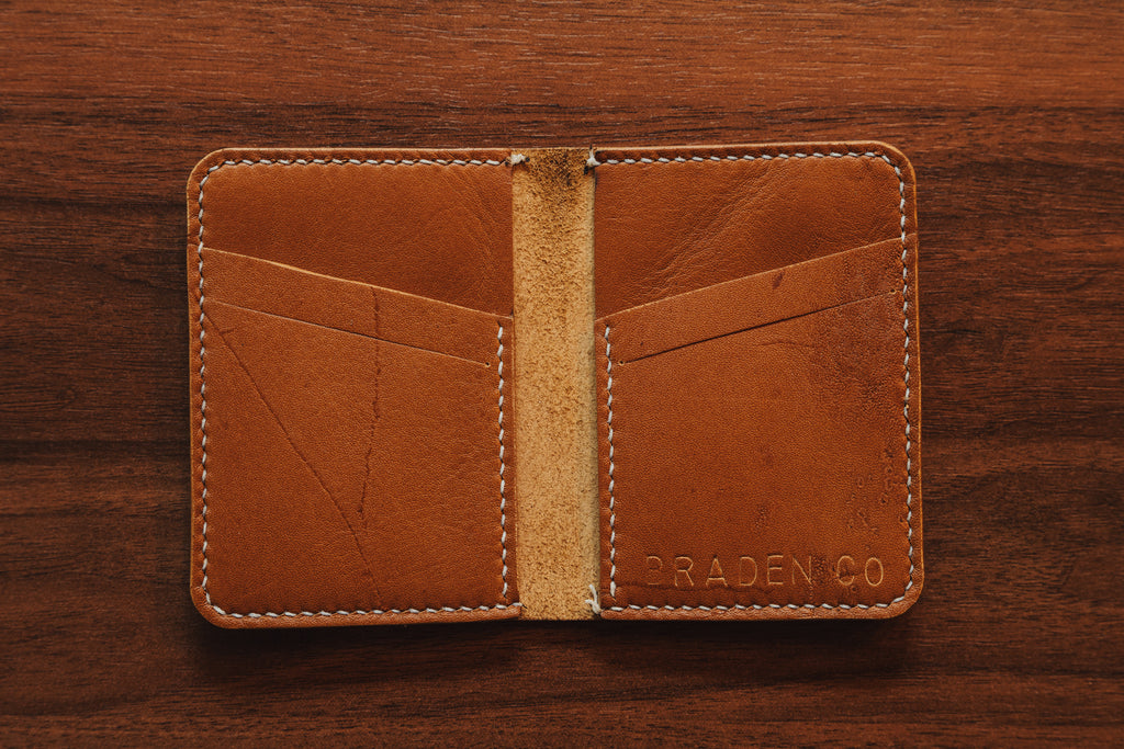Brown leather wallet with 'Braden Co' branding on a wooden surface