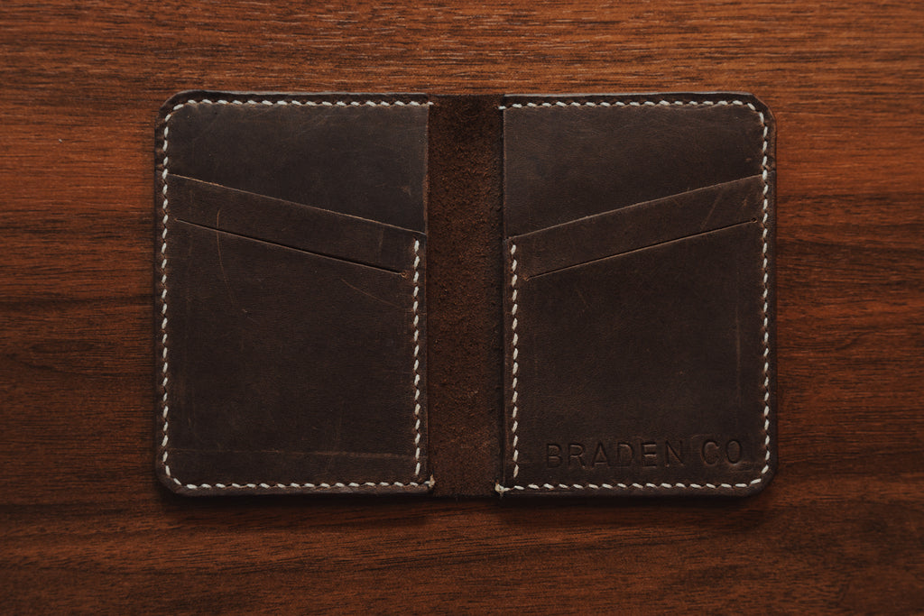 Brown leather wallet with visible branding on a wooden surface