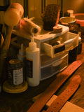 Workbench with various items including a bottle, brush, and wooden object.