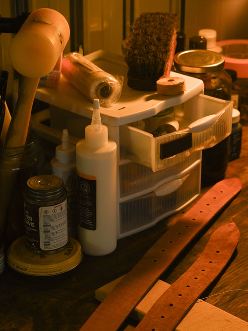 Workbench with various items including a bottle, brush, and wooden object.